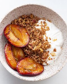 a bowl filled with peaches and granola topped with yogurt on top