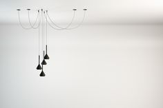 a group of black hanging lights in a white room