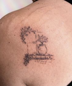 the back of a woman's shoulder with a vase and flowers tattoo on it