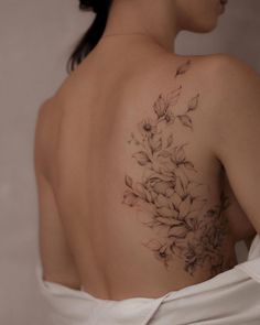 the back of a woman's shoulder with flowers tattooed on her left arm and chest