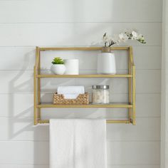 a shelf with towels, soaps and other items on it in a white bathroom