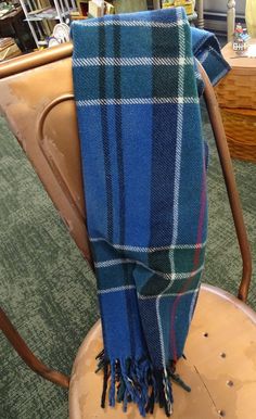 a blue and green plaid blanket sitting on top of a wooden chair in a room