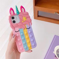 a person holding up a phone case with a unicorn on it