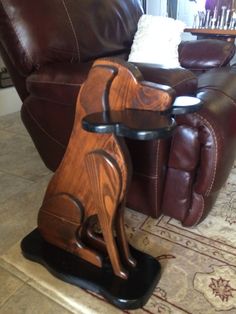 a wooden dog sitting on top of a table next to a brown leather chair in a living room