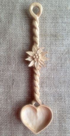 a wooden spoon with a heart and flower decoration hanging from it's side on a table