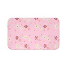 a bath mat with pink flowers and white dots on it's side, in front of a white background