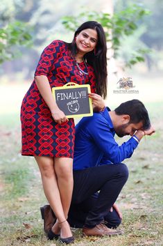 a man kneeling down next to a woman holding a chalkboard with the words finally written on it