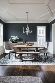 an elegant dining room with blue walls and wood flooring, chandelier above the table