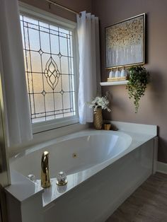 a bath tub sitting under a window next to a vase with flowers on top of it