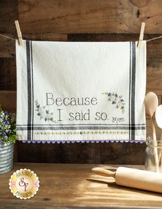 a kitchen towel hanging on a clothes line with wooden utensils next to it