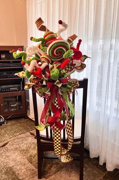 a christmas decoration on top of a wooden chair in front of a window with curtains