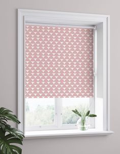 a pink and white patterned roman blind in front of a window with potted plant