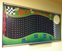 a race track sign hanging on the wall in a school room with numbers and colors