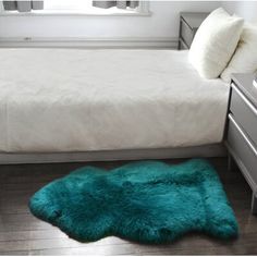 a bed with a green rug on the floor in front of it and a window