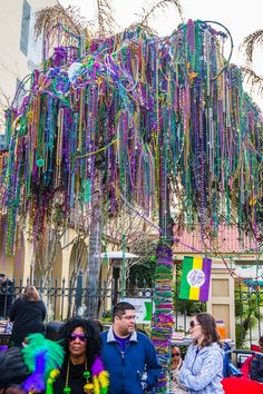 a group of people standing under a tree covered in beads