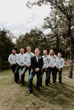 a group of men standing next to each other on top of a grass covered field