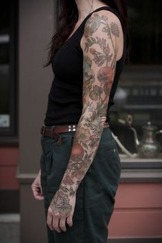 a woman with tattoos on her arm and arms is standing in front of a store