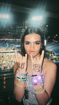 a woman with her hands in the air and tattoos on her hand, at a concert