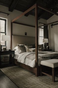 a bedroom with a four poster bed and white linens on the pillows, along with a bench