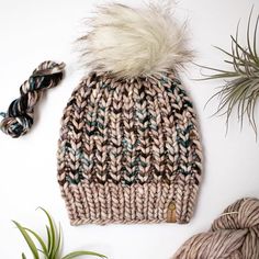 a knitted beanie with a white and green pom - pom