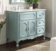 a bathroom with a blue vanity, mirror and potted plant on the sink counter