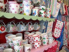 there are many cups and mugs on display