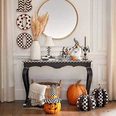 a black and white table with pumpkins on it in front of a round mirror