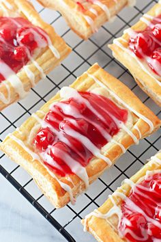 strawberry shortbreads with white icing and drizzled on top are cooling on a wire rack