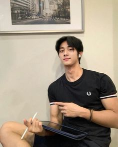 a young man sitting on the floor holding a pair of white chopsticks in his hand