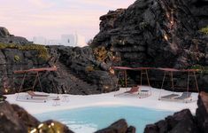 an outdoor hot tub in the middle of a rocky area with swings and tables on it