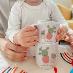 two children's hands holding mugs with cactus designs on them at a table