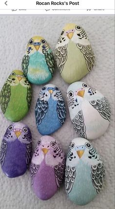 several colorful birds painted on rocks sitting next to each other