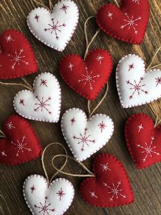 several red and white heart ornaments hanging from twine on a wooden table with string