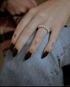 a woman's hand with some tattoos on it and a pearl beaded ring