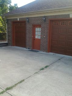 a fire hydrant in front of two garages with brown doors and brick walls