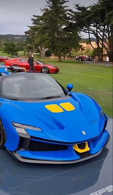 the blue sports car is parked in front of several other red and yellow cars on display