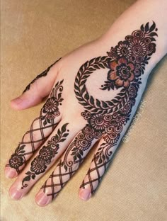 a hand with henna on it that is decorated with flowers and leaves in the shape of a circle