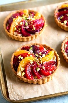 small tarts with fruit and nuts are on a baking sheet