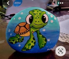 a painted rock with a turtle on it's face and laptop in the background