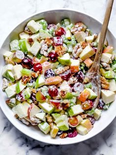 a white bowl filled with apples, celery, walnuts and cranberries