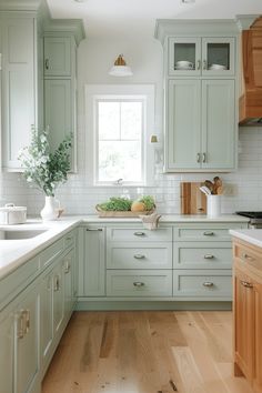 a kitchen with light green cabinets and wood floors