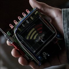 a person holding an electronic device in their hand with wires attached to the inside of it