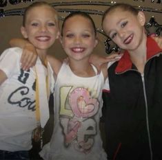 three young children posing for the camera with their arms around each other