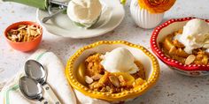 two bowls filled with dessert sitting on top of a table next to cups and spoons