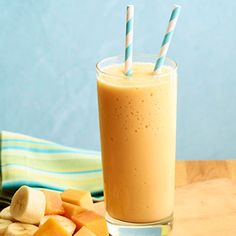 a smoothie with two straws in it sitting on a table next to sliced bananas