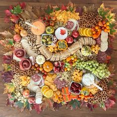 a table topped with lots of different types of food and autumn leaves on top of it