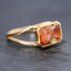 This stunning 14k yellow gold and sunstone statement ring features a solitaire emerald cut color changing sunstone in a bezel setting. This beautiful sunstone features shades of orange, red, yellow and green depending on how the light hits it! The ring itself features a split shoulder style giving more room for light to shine through this beautiful stone. This beautiful high polish cocktail ring makes for a great statement! Stone Significance: Known as the stone of joy, sunstone is said to inspire good nature + an enjoyment of life. It is highly effective in cleansing auras and chakras.⊹ 14k Yellow Gold + Sunstone⊹ Stamp reads 14k⊹ Excellent Condition⊹ Ring Size: 7⊹ Sunstone: 12.1mm x 8mm, Approx 3.98 TCW Sunset Ring, Ring Square, Gold Filled Ring, Yellow And Green, Shades Of Orange, Green Tourmaline, Bracelets And Charms, Gift Accessories, Cocktail Ring