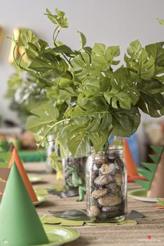 there is a plant in a jar on the table with other party hats around it