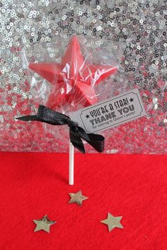 a star shaped lollipop on top of a red table with silver sequins