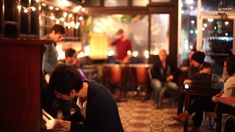 a man sitting at a table in a restaurant writing on a piece of paper while others look on